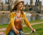 Frau mit Fahrrad am Elbufer in Dresden im Frühling, im Hintergrund die Altstadt mit der Frauenkirche – ideal für Stadtführungen mit Gutschein.