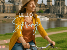 Frau mit Fahrrad am Elbufer in Dresden im Frühling, im Hintergrund die Altstadt mit der Frauenkirche – ideal für Stadtführungen mit Gutschein.