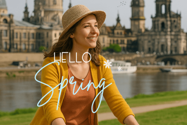 Frau mit Fahrrad am Elbufer in Dresden im Frühling, im Hintergrund die Altstadt mit der Frauenkirche – ideal für Stadtführungen mit Gutschein.