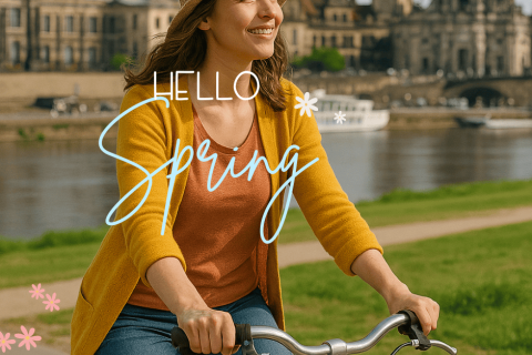 Frau mit Fahrrad am Elbufer in Dresden im Frühling, im Hintergrund die Altstadt mit der Frauenkirche – ideal für Stadtführungen mit Gutschein.