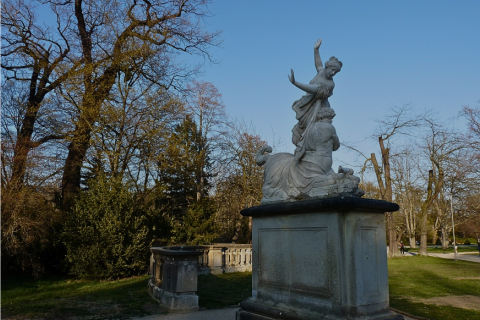 Steinskulptur zweier Figuren im Großen Garten Dresden, umgeben von frühjährlich sprießenden Bäumen und historischem Steinbalustraden-Element
