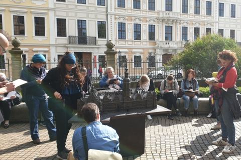 Glückliche Tourist*innen bei einer Stadtführung in Dresden, lachend vor historischer Kulisse.