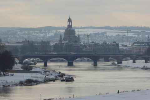 Winterliche Ansicht der Dresdner Altstadt mit verschneiten Dächern, der Elbe und den historischen Brücken im Vordergrund.