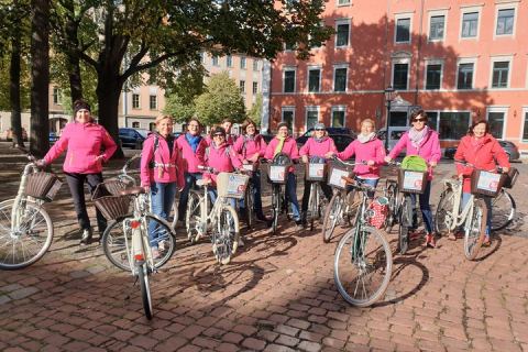 Gruppe von Frauen mit Fahrrädern bei einer geführten Radtour durch Dresden, Startpunkt auf einem Platz mit Kopfsteinpflaster und Altbauten im Hintergrund