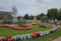 Gruppe von Menschen mit Fahrrädern während einer Stadtführung im Großen Garten Dresden, vor barockem Palais und Blumenbeeten mit Statue